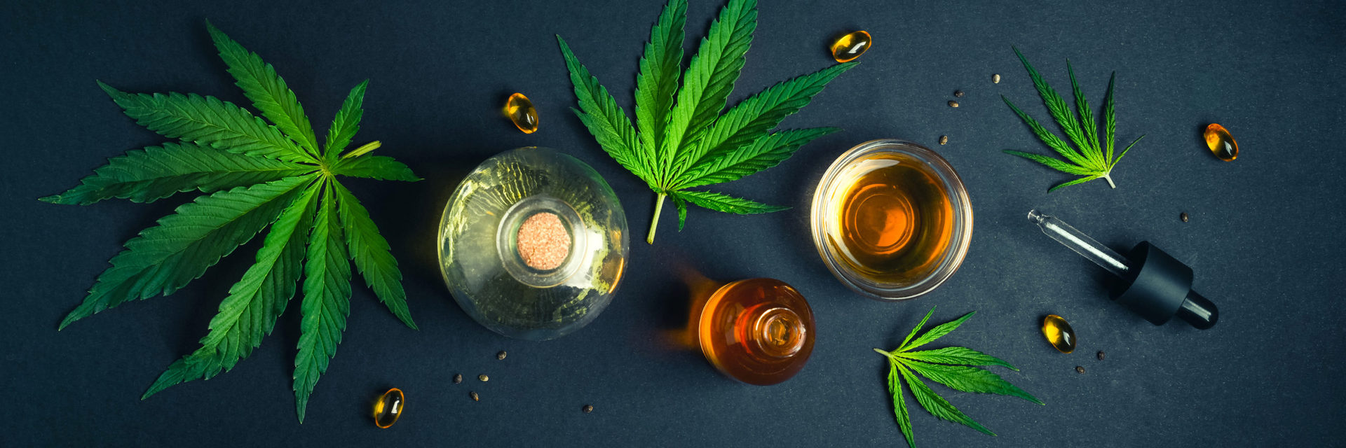 Medical CBD oil on black trendy background with cannabis leaves.
