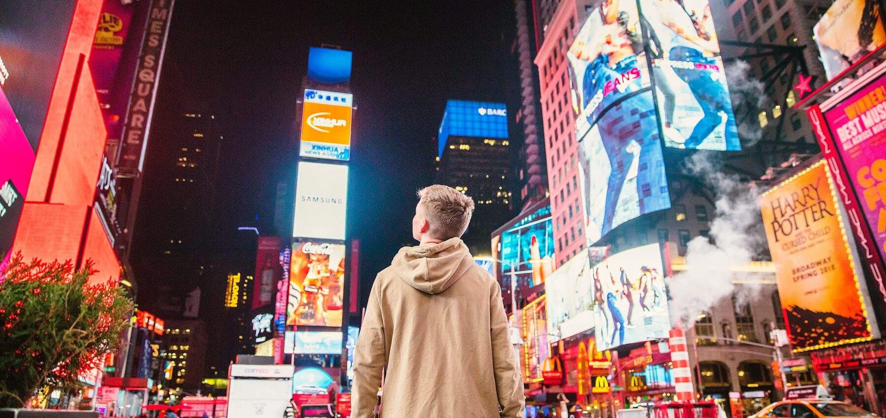 boy looks up at digital out of home advertisements in times square