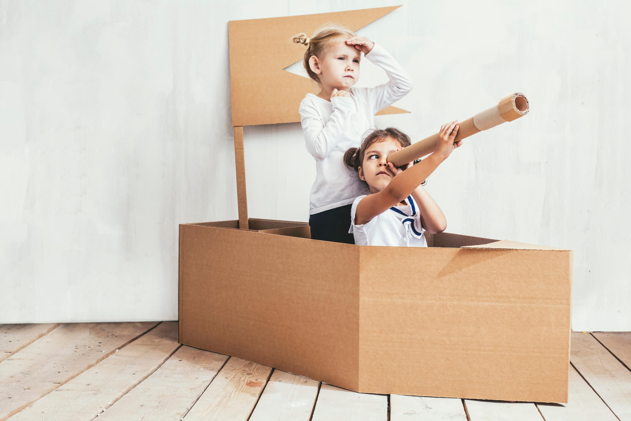 Two children searching for dry land in their cardboard box pirate ship.