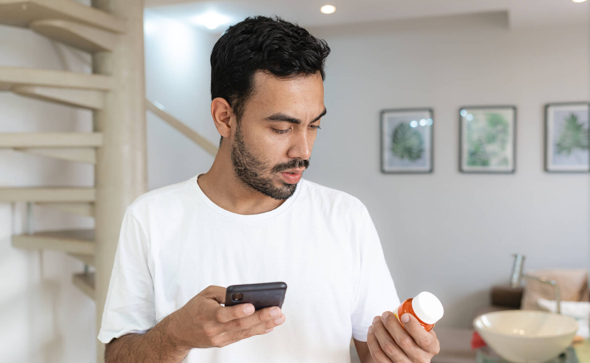 Man looking at prescription bottle and phone