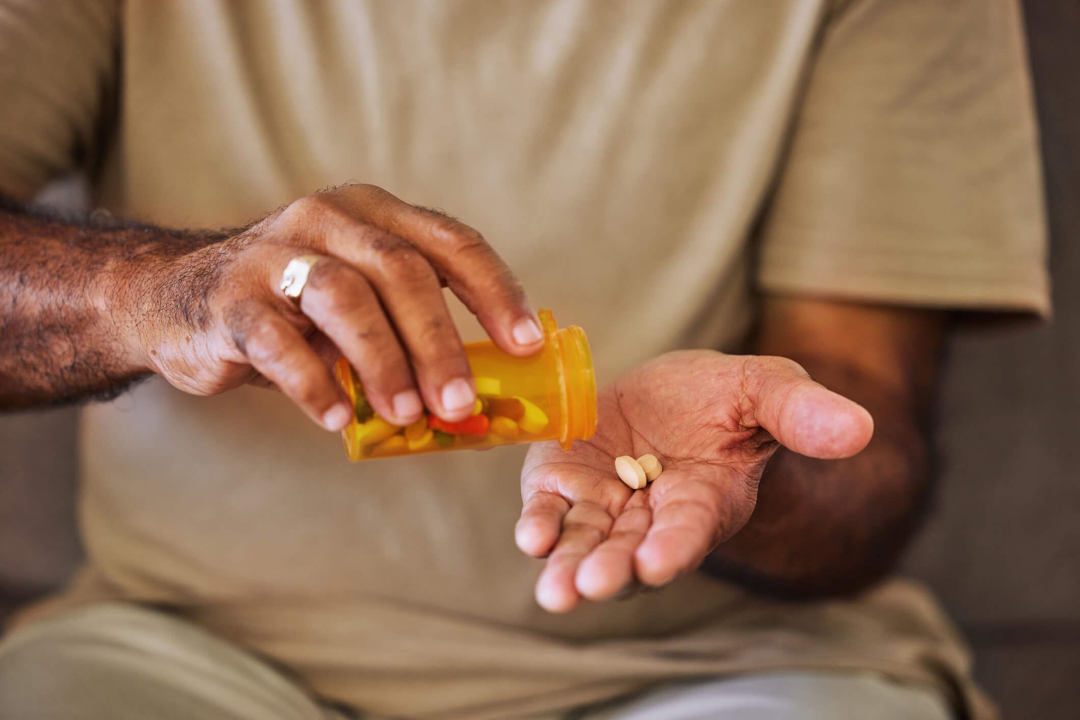 A person pouring prescription pills out of a bottle into their hand.