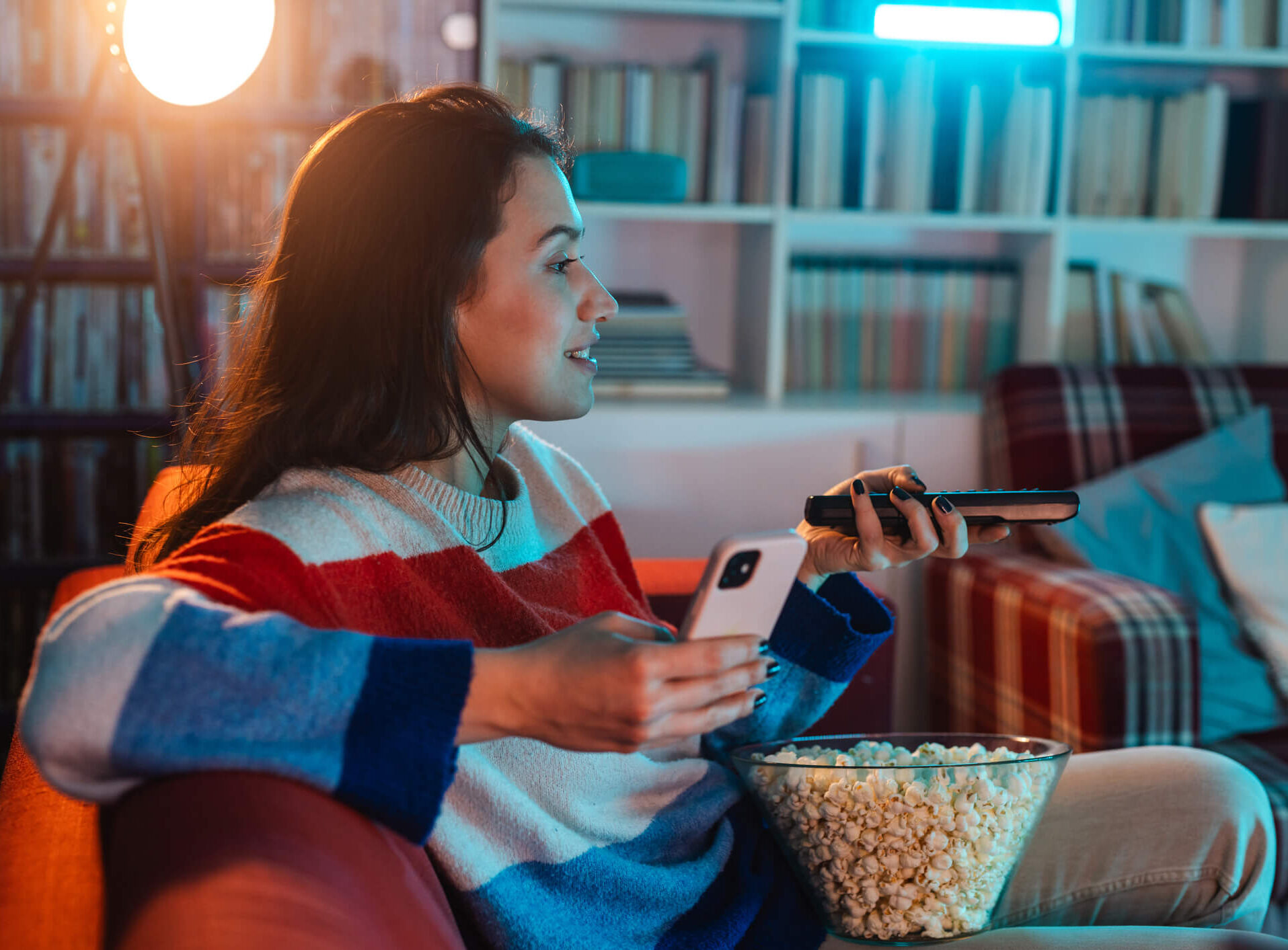 Woman watching TV while holding her phone as if she's also watching something on her phone