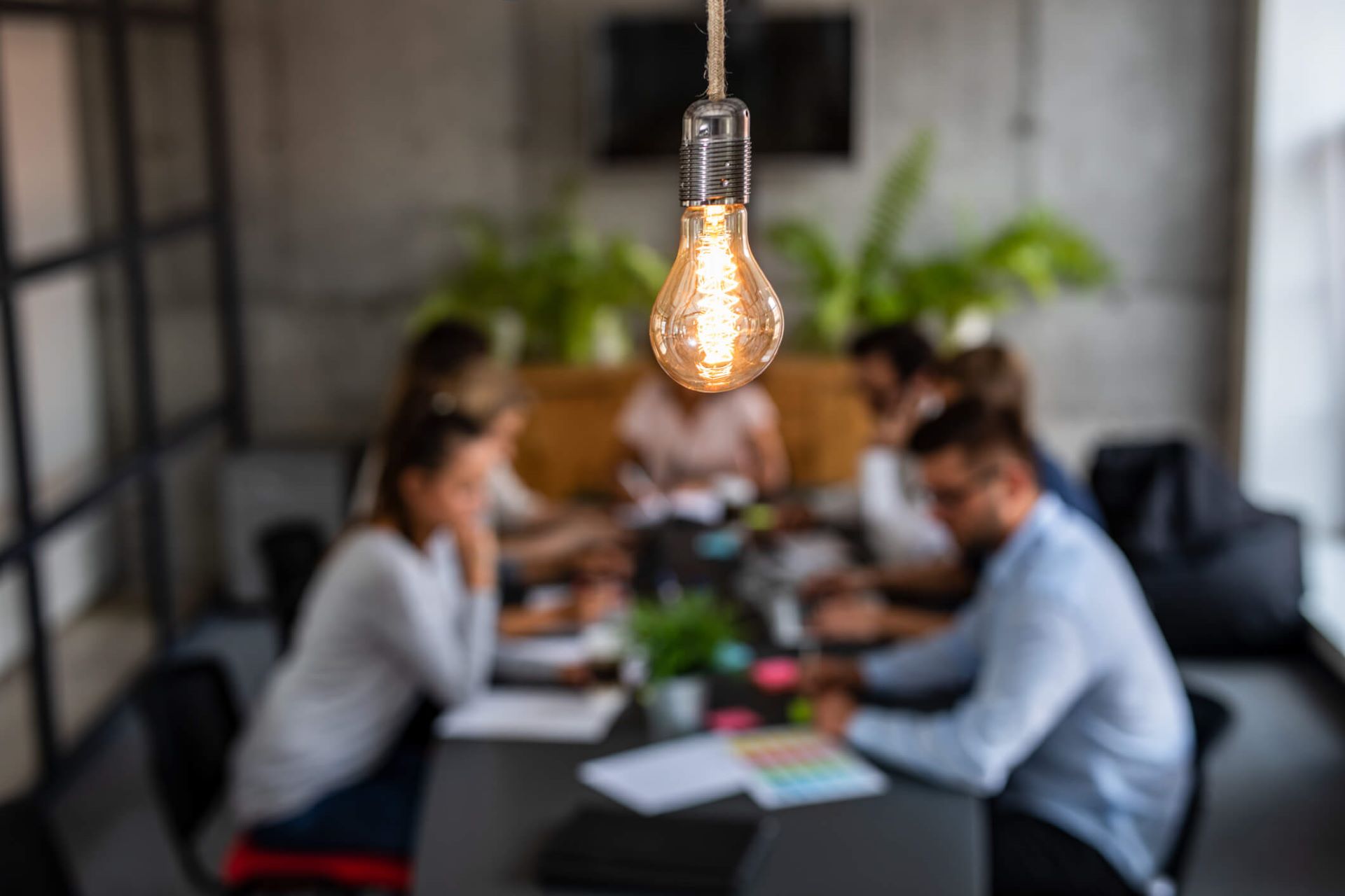 An image showing advertising agency professionals meeting around a desk with a lightbulb in focus.