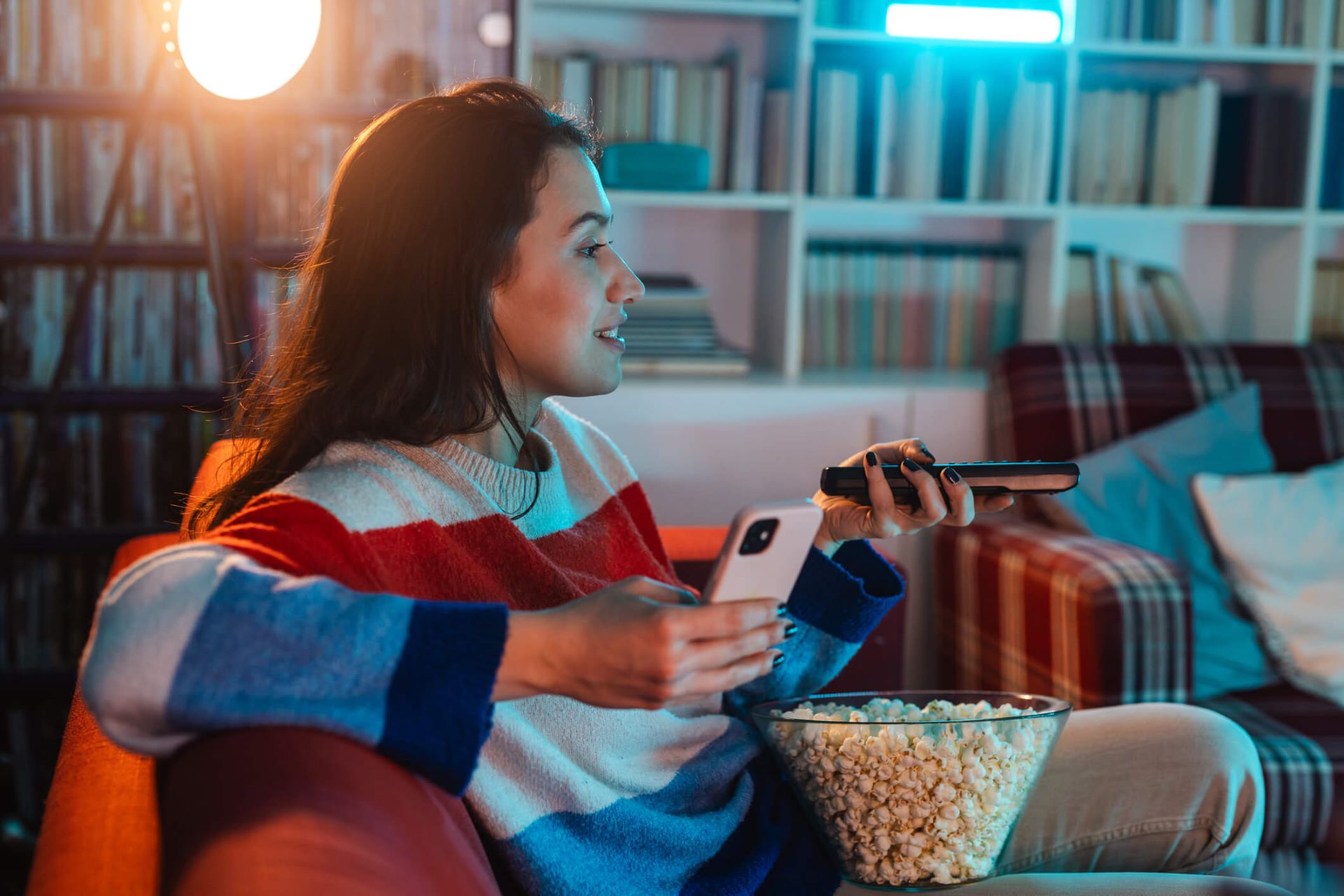 An image of a woman watching connected TV while holding her phone