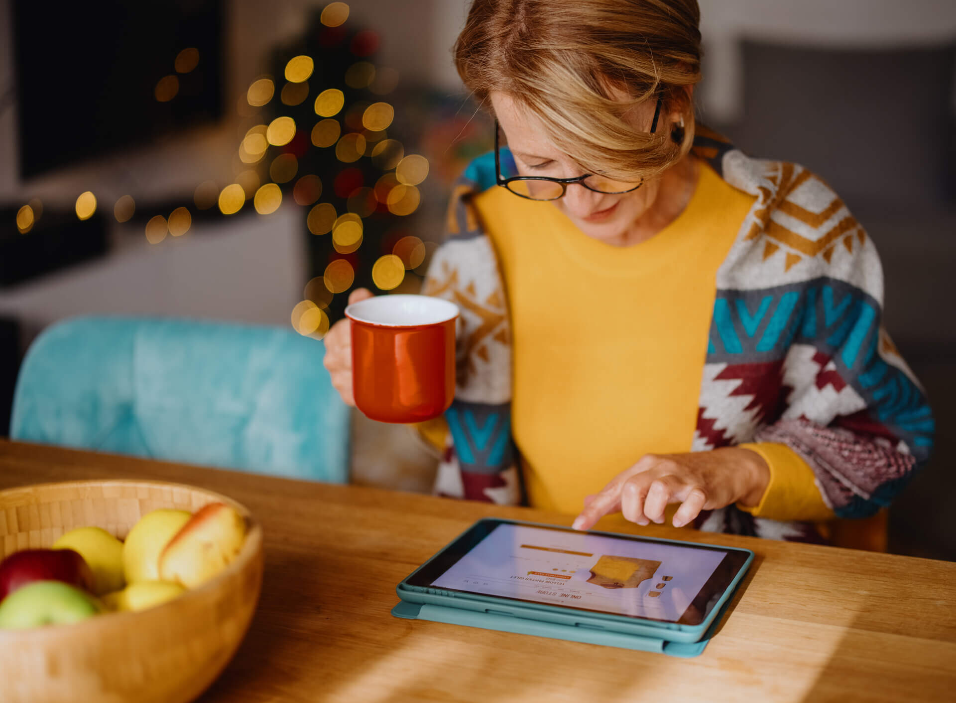 Woman shopping on her tablet with holiday lights in the background