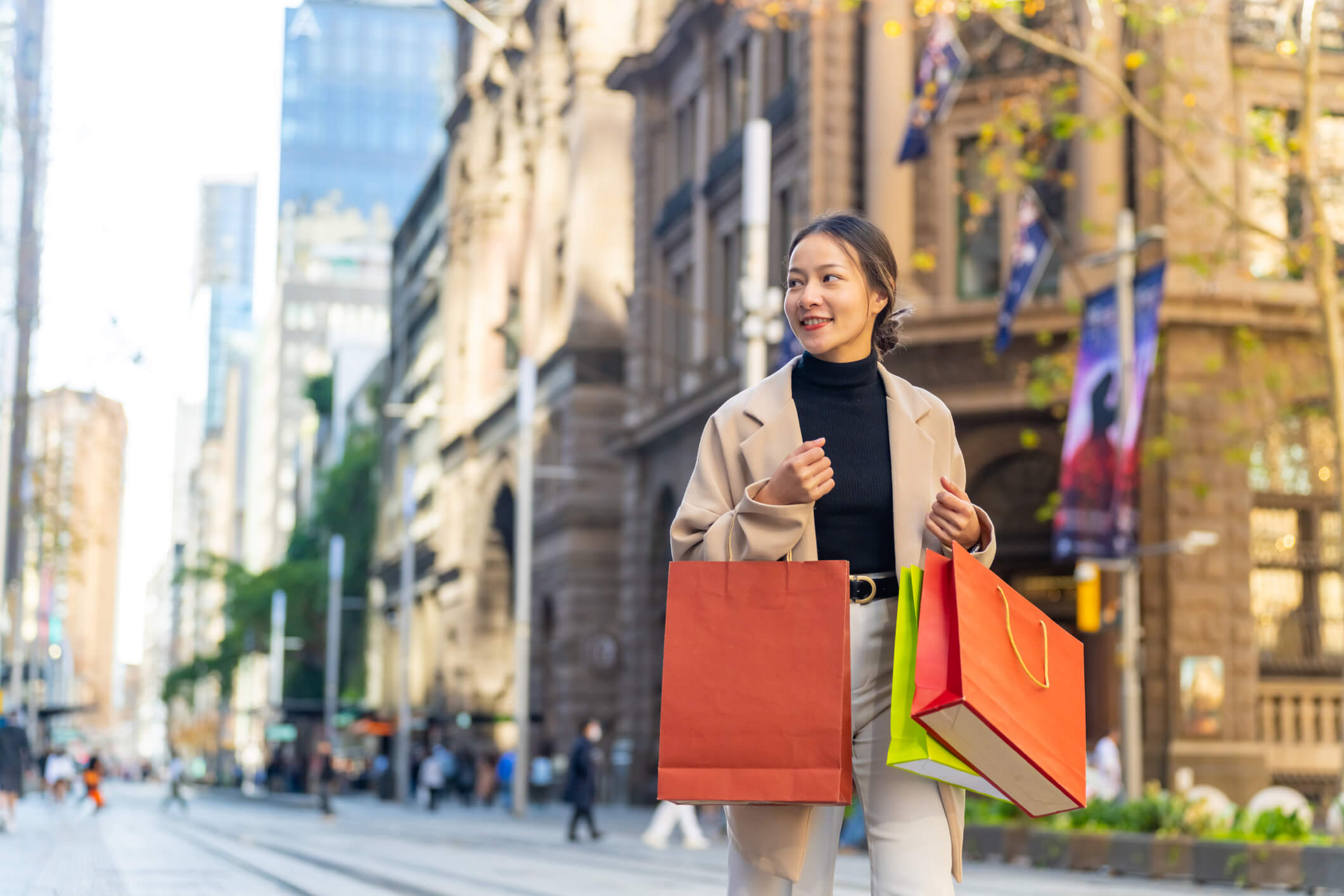 A woman carries two shopping bags after doing some of her 2025 holiday shopping.