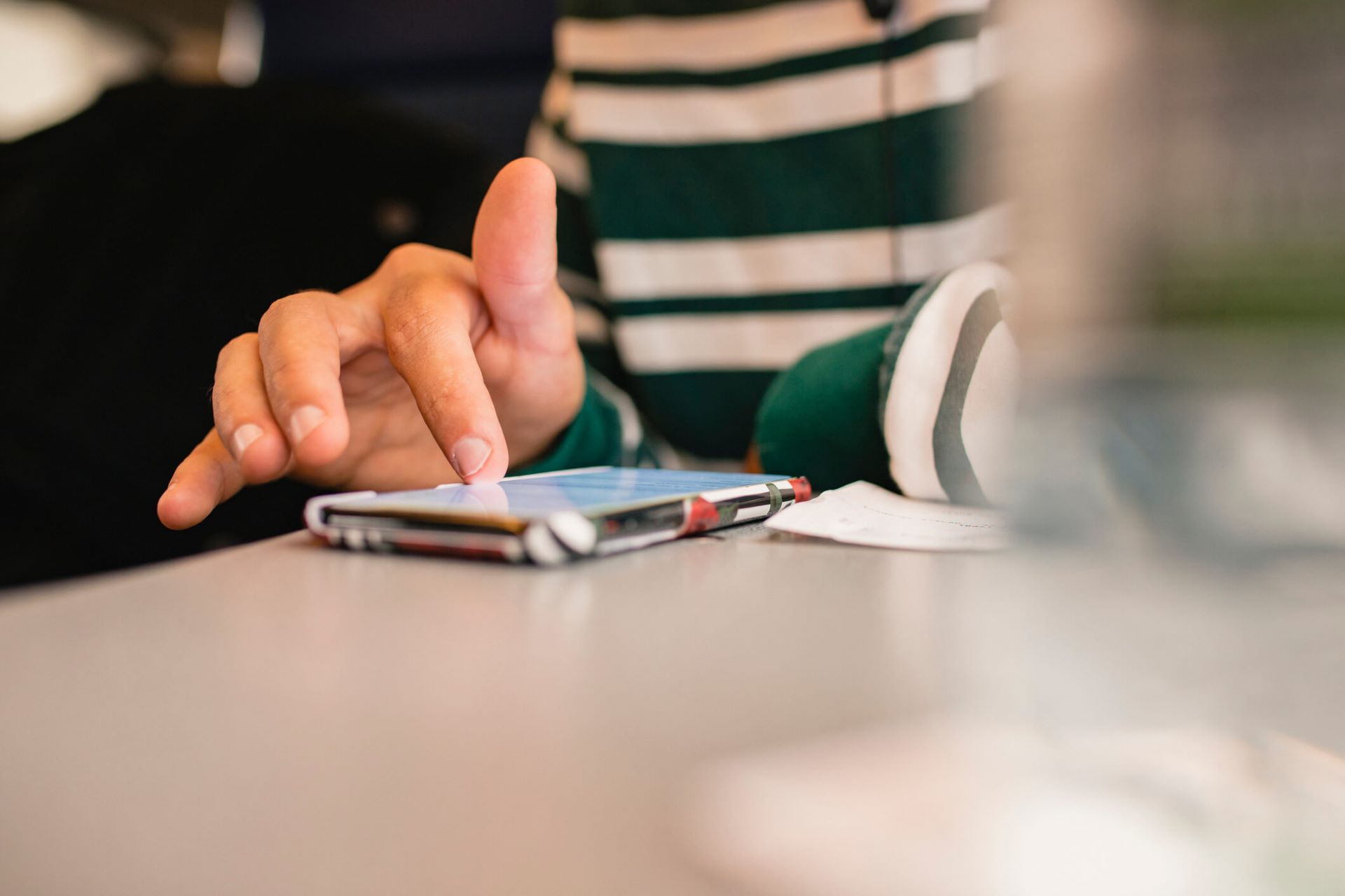 An image showing a person sitting at a table scrolling through their smartphone