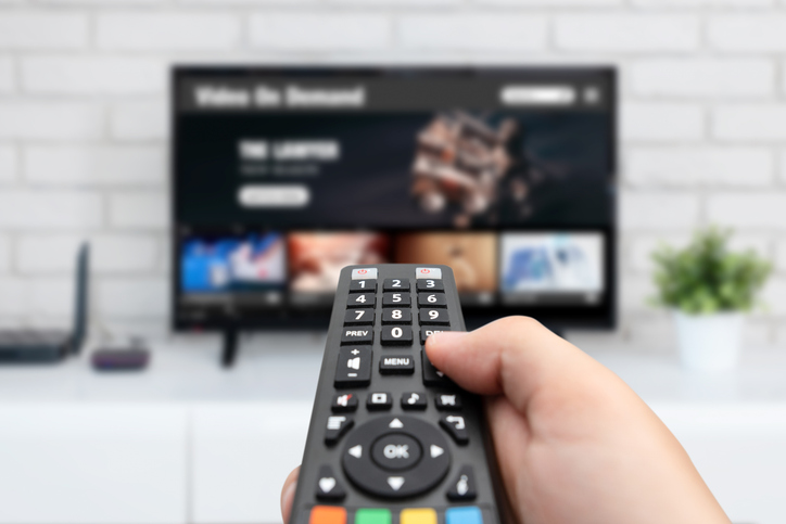 hand holding a TV remote to select a live CTV program