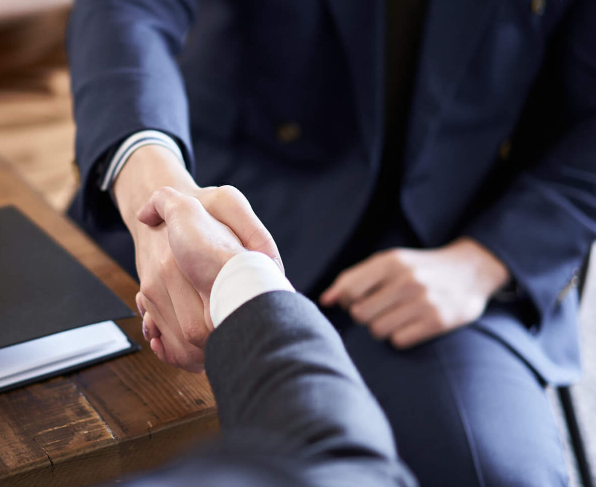 Hands of business people wearing suits shaking across a table