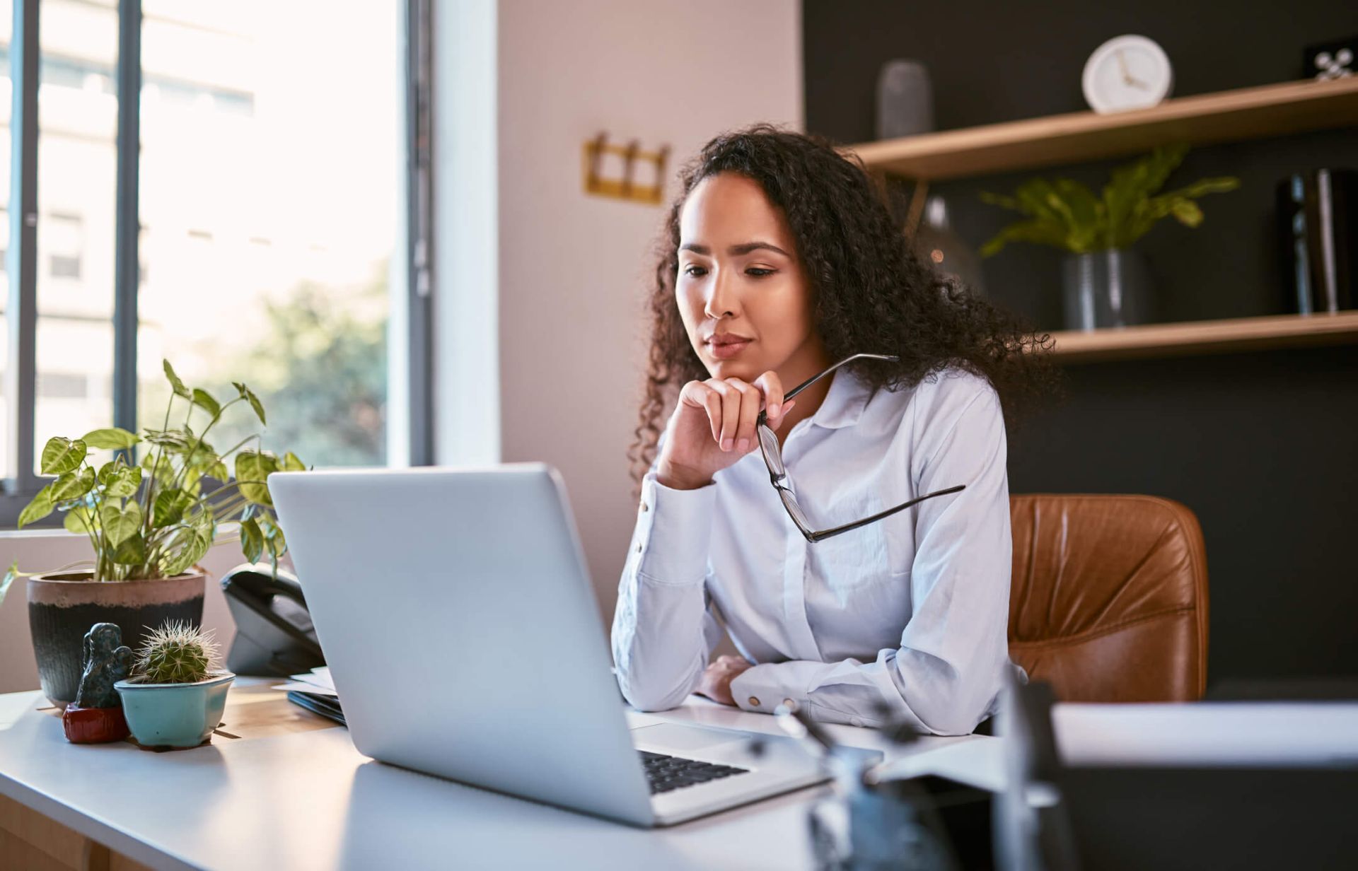 An image of an advertising agency leader sitting at her desk and reading an article on her laptop.