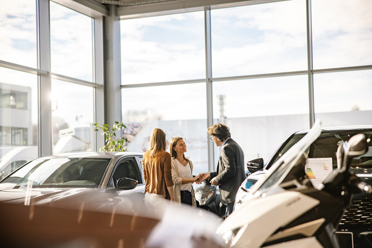 auto dealer is giving the keys to a customer at a car dealership