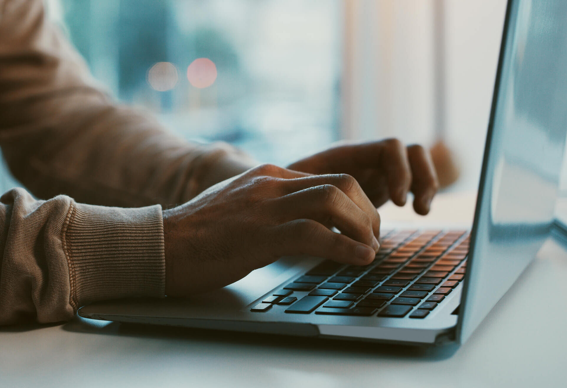 Hands typing on a laptop