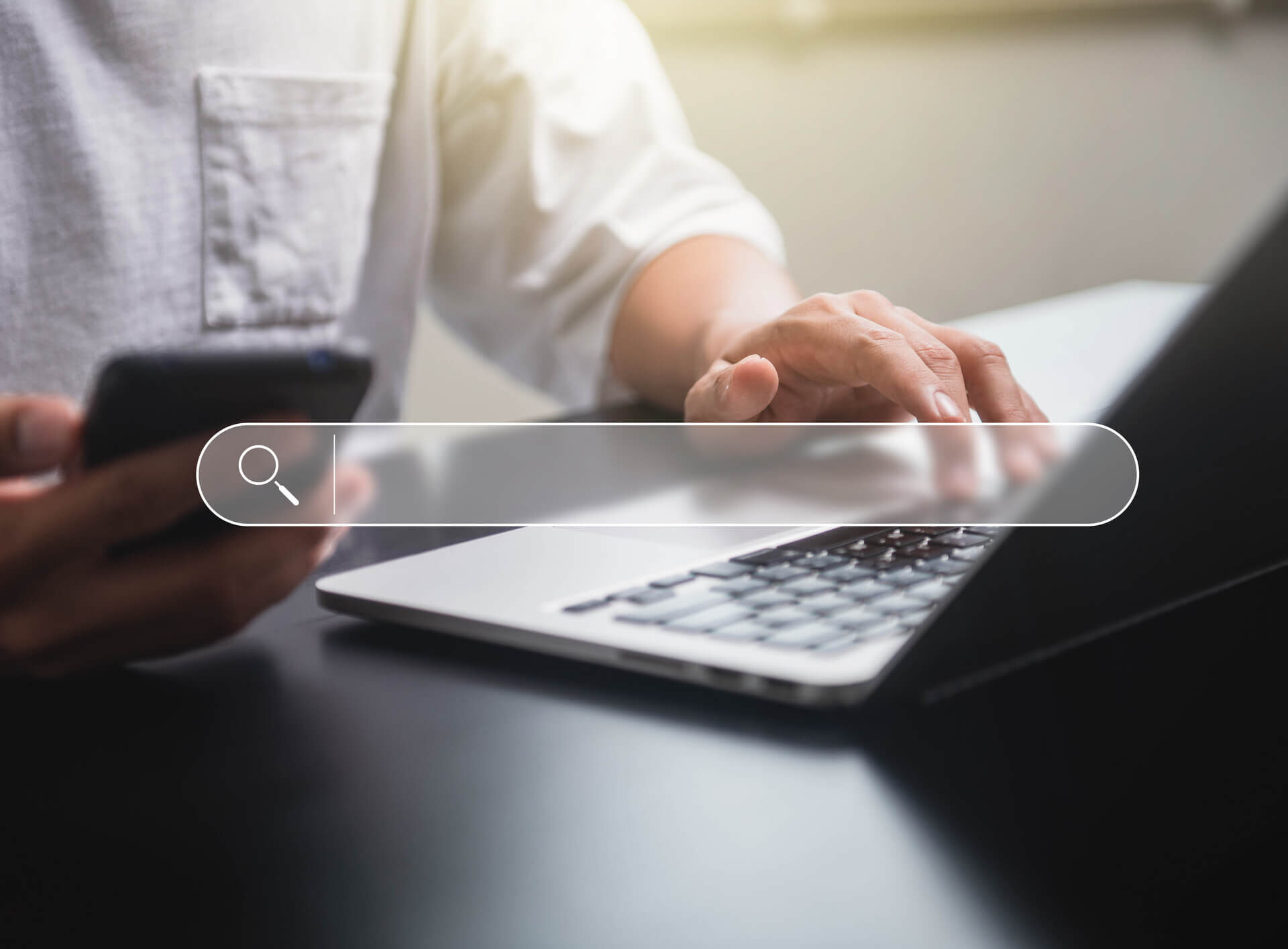 Man searching online on phone and laptop