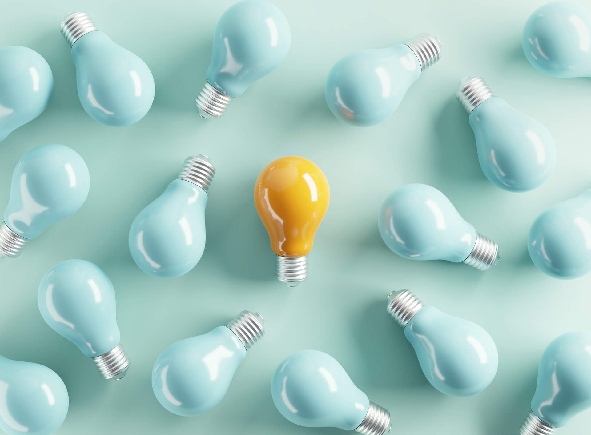 One yellow lightbulb stands out amongst many blue lightbulbs