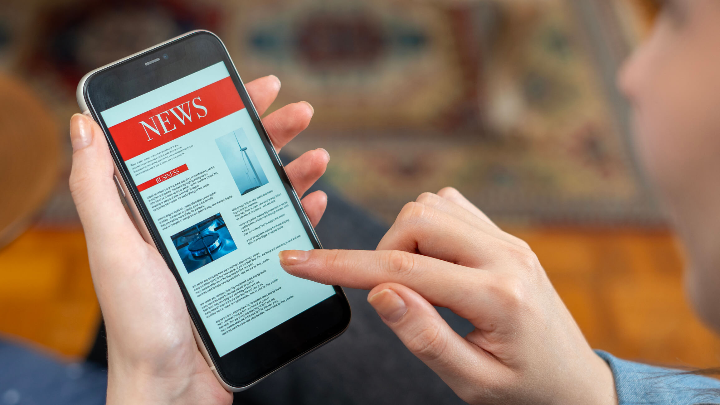 Hands holding a phone displaying news content